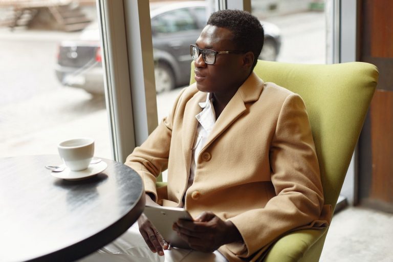 Pensive elegant businessman with tablet in cafe